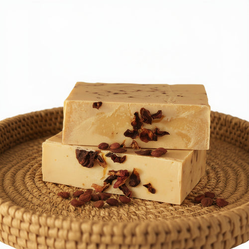 Two rectangular soap bars with dried flowers embedded on a gray surface.