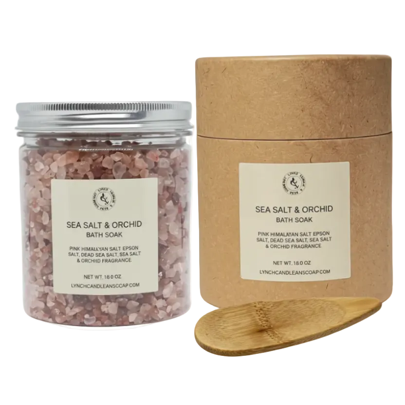 Sea Salt & Orchid bath soaks in a jar and cardboard container with a wooden scoop on a white background.