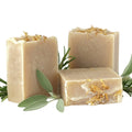 Two bars of rosemary and sage soap with calendula petals on a white background