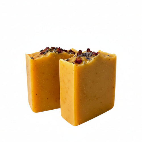 Two yellow soap bars with visible ingredients on a white background
