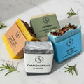 Four soaps with different scents and designs on a striped fabric background