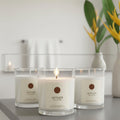 Vetiver candle on bathroom sink top next to a vase of yellow flowers